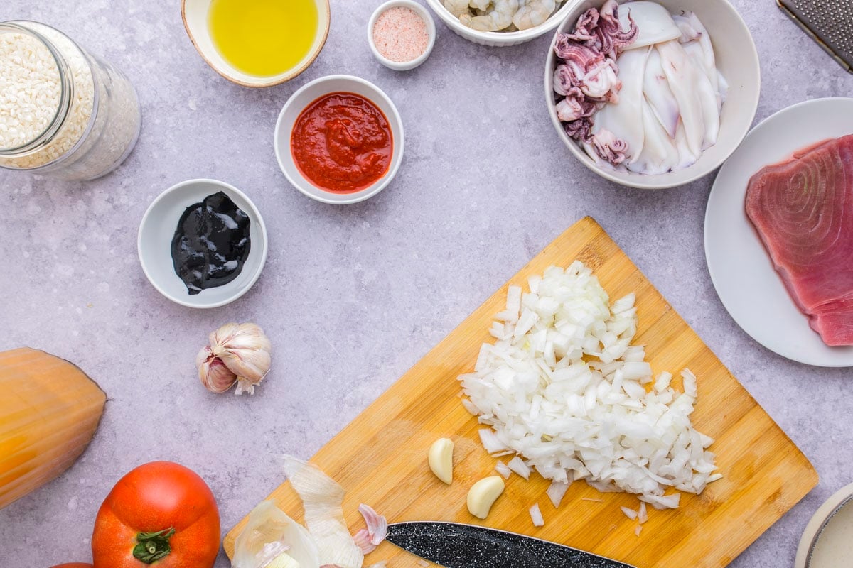 onion chopped on wooden cutting board with black knife beside.