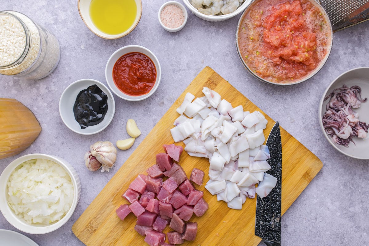 chopped pieces of fish on wooden cutting board with knife beside.
