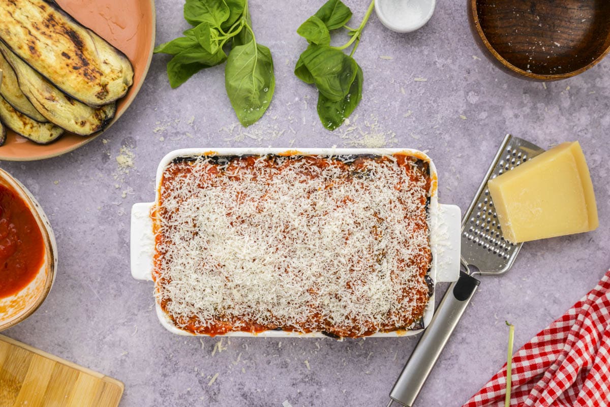 eggplant parmesan in white baking dish covered in shredded parmesan.