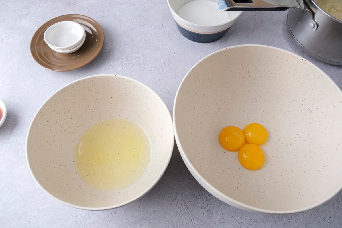 egg separated into yolks and white in two bowls on counter.