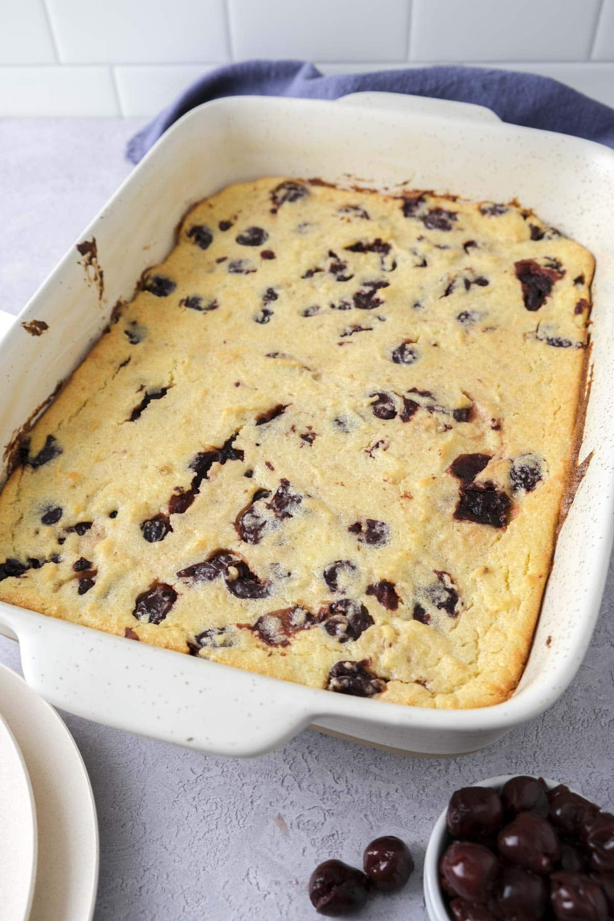 baked semolina casserole with cherries in baking pan on counter.