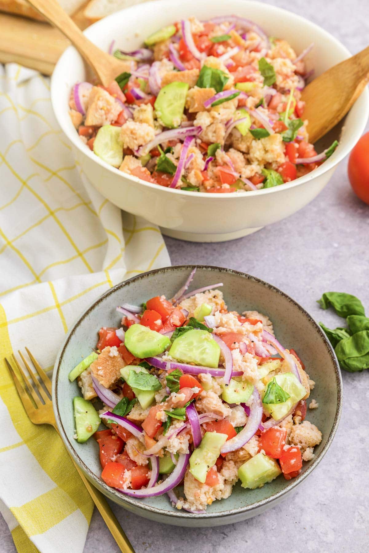 serving bowl of panzanella salad with smaller serving bowl in front on counter.