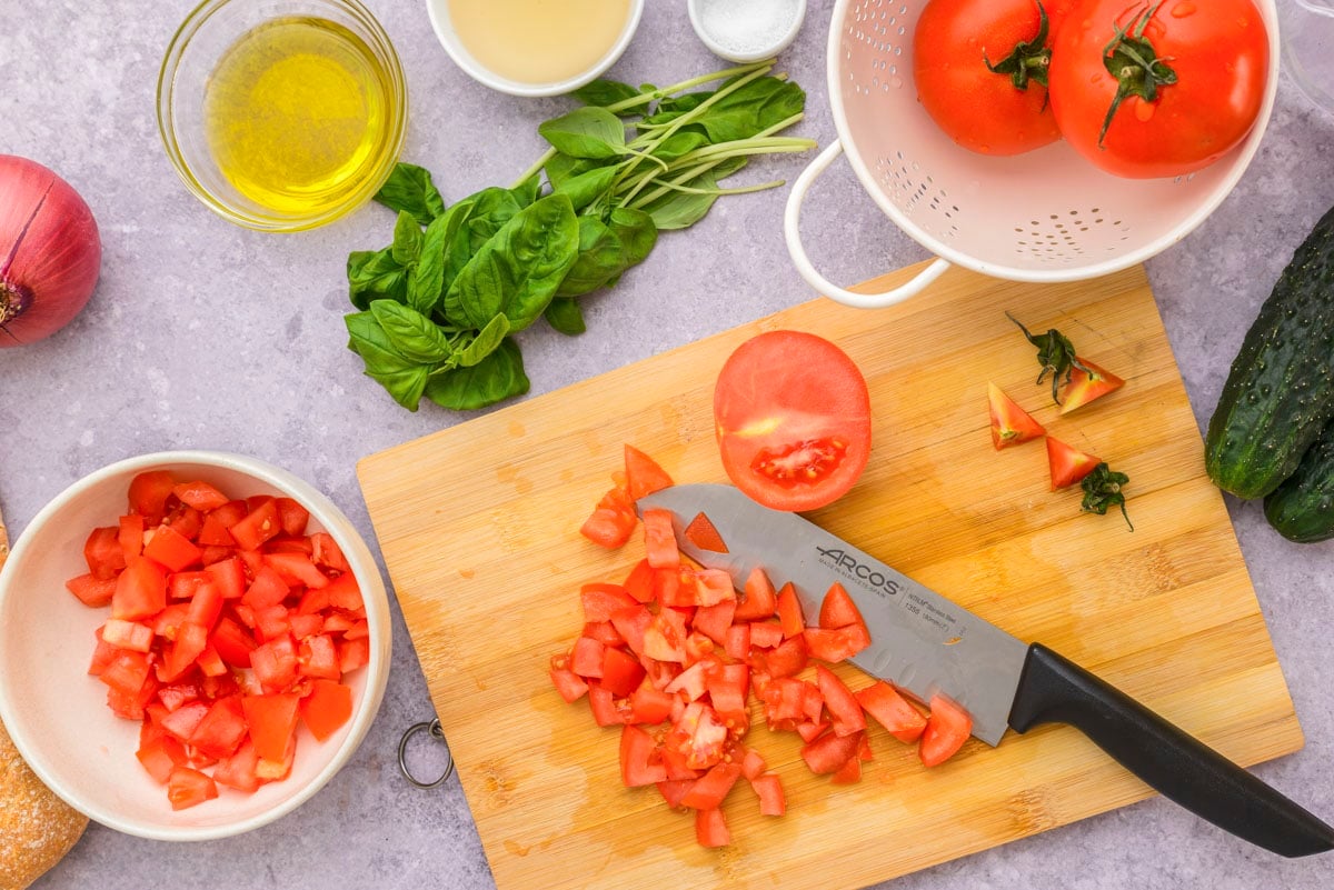 tomatoes diced on wooden cutting board with knife beside.