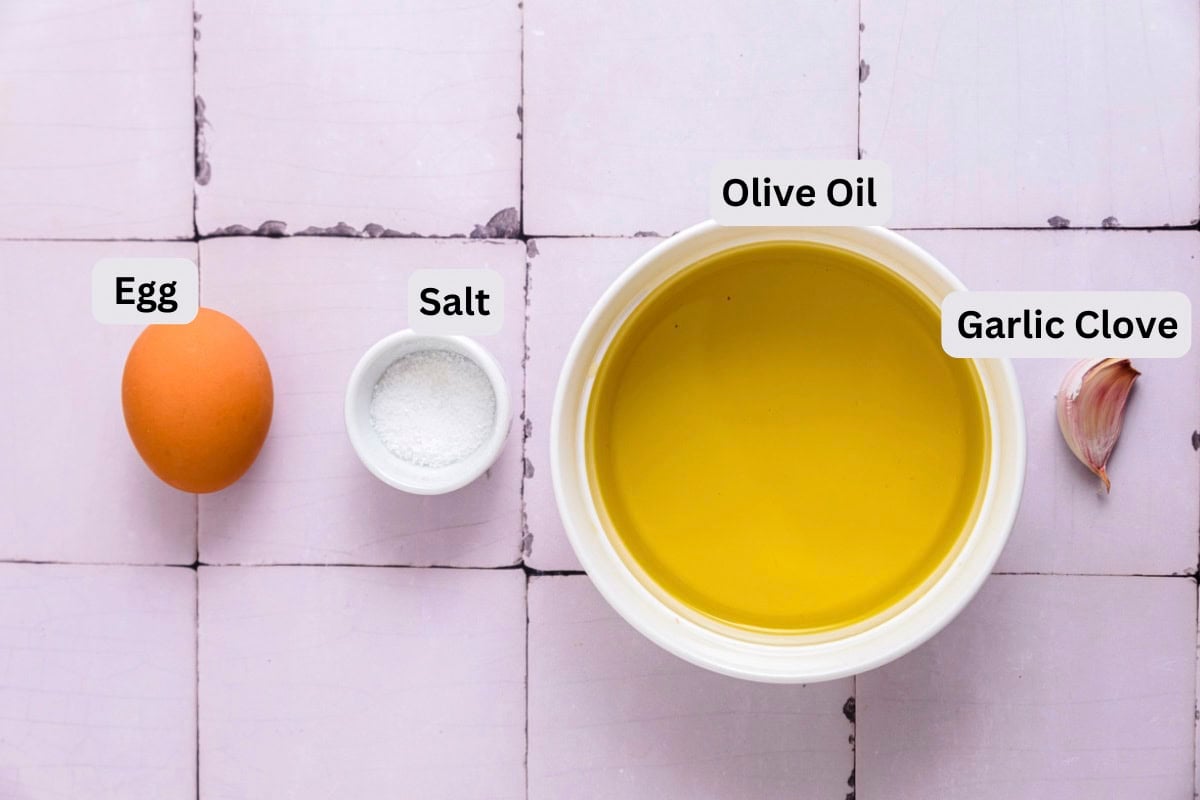 ingredients to make spanish garlic sauce on counter in bowls with labels.
