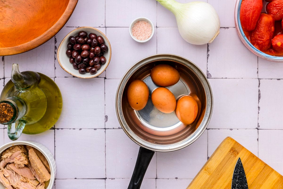 hard boiled eggs in silver pot sitting on counter top.