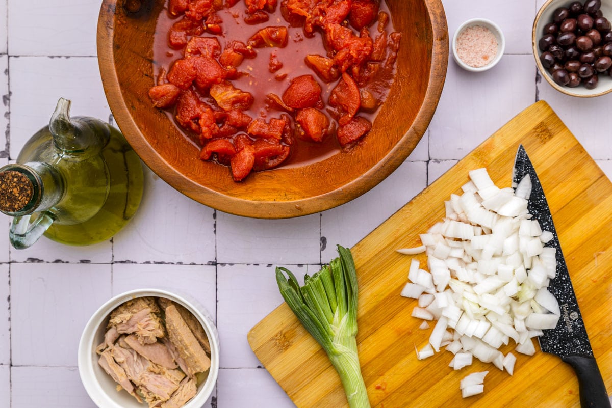 onions diced on wooden cutting board with knife beside sitting on counter.