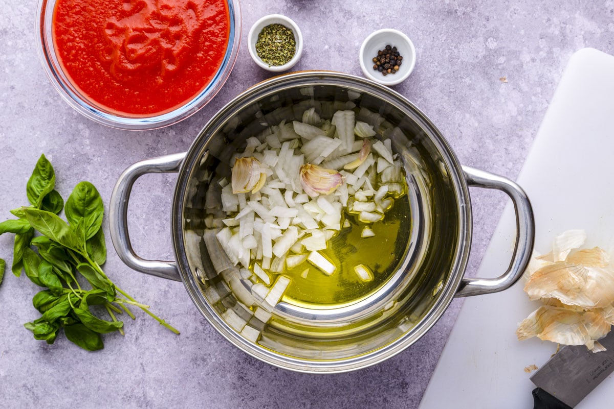 diced onions and garlic in metal pan with counter top around.