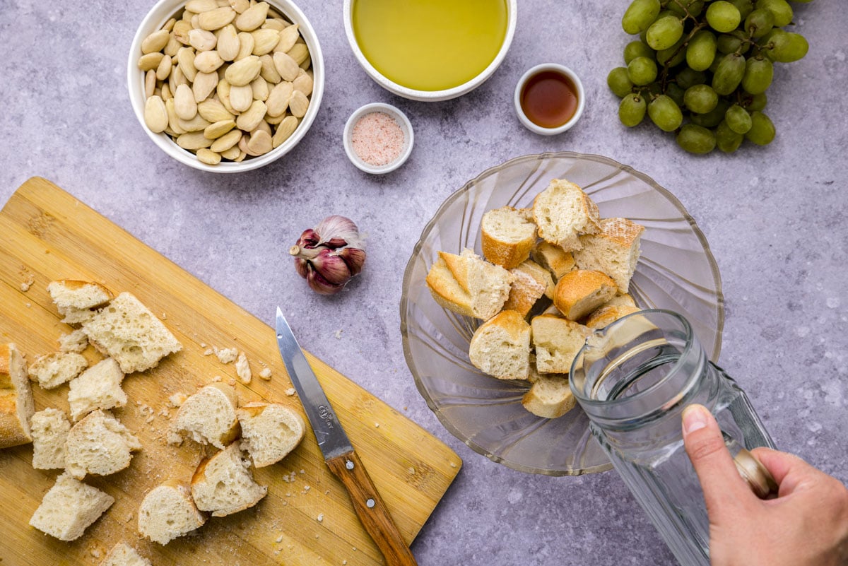 pieces of stale bread in glass bowl on counter with water being poured into it.