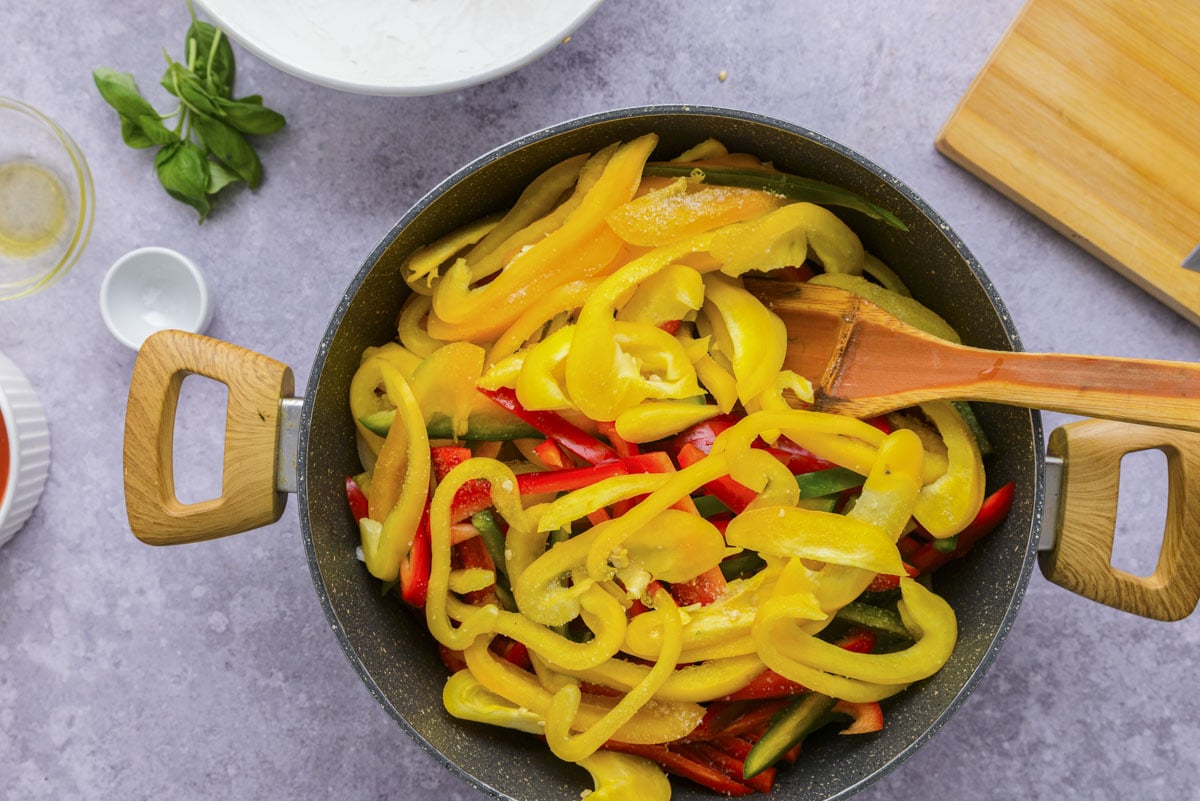 cut bell pepper in black frying pan with counter around.