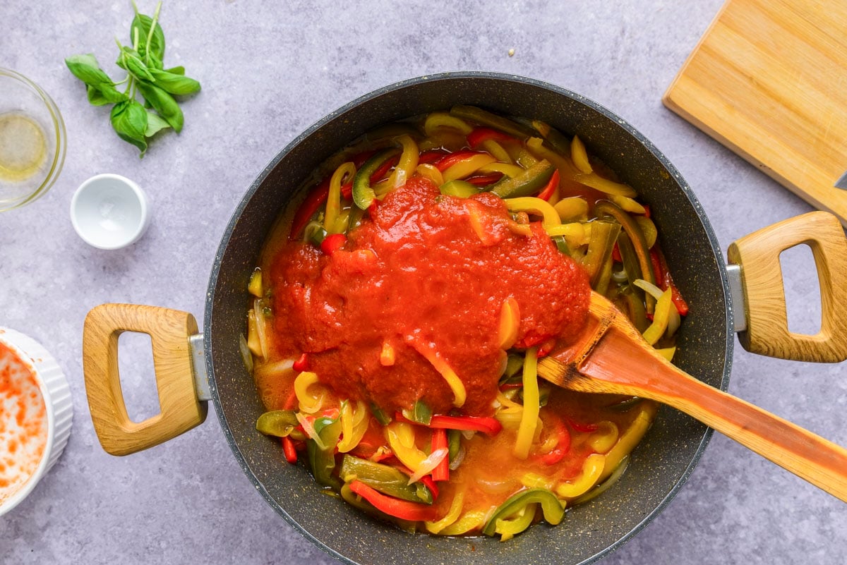 tomato sauce in black frying pan with cut bell peppers.