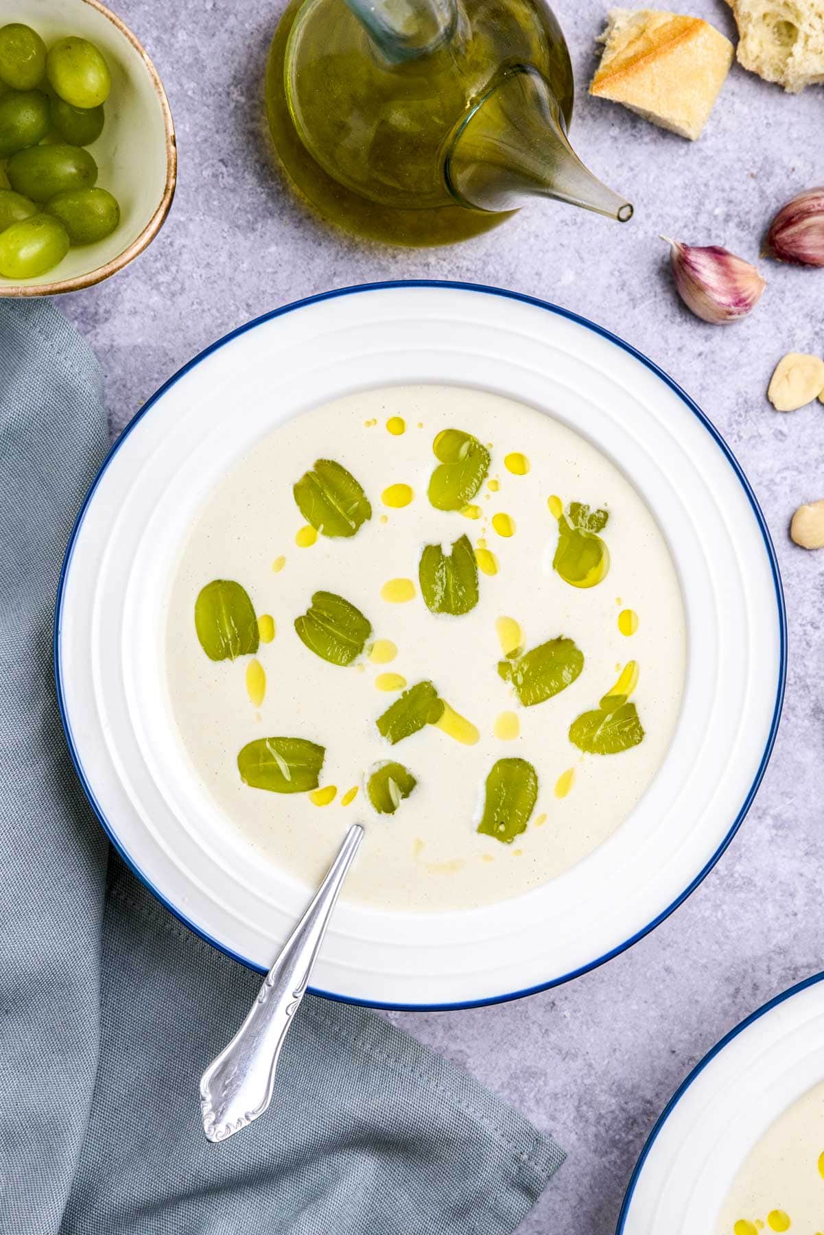 bowl of white gazpacho with sliced grapes on top sitting on counter.