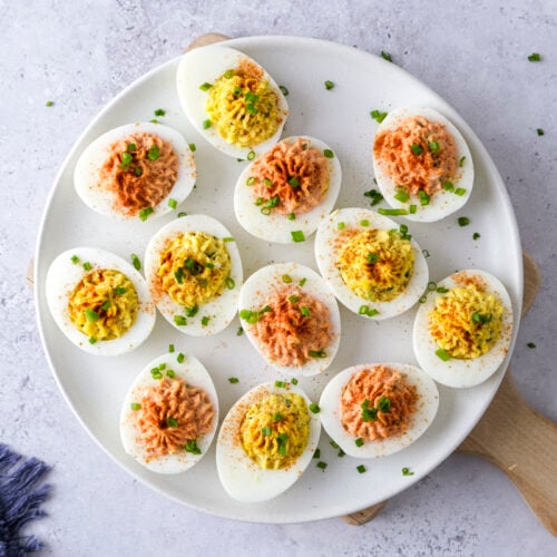 white plate of deviled eggs sitting on counter.