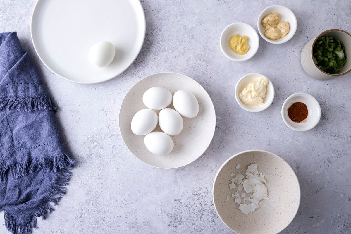 hard boiled eggs with shells removed on counter with spices around.