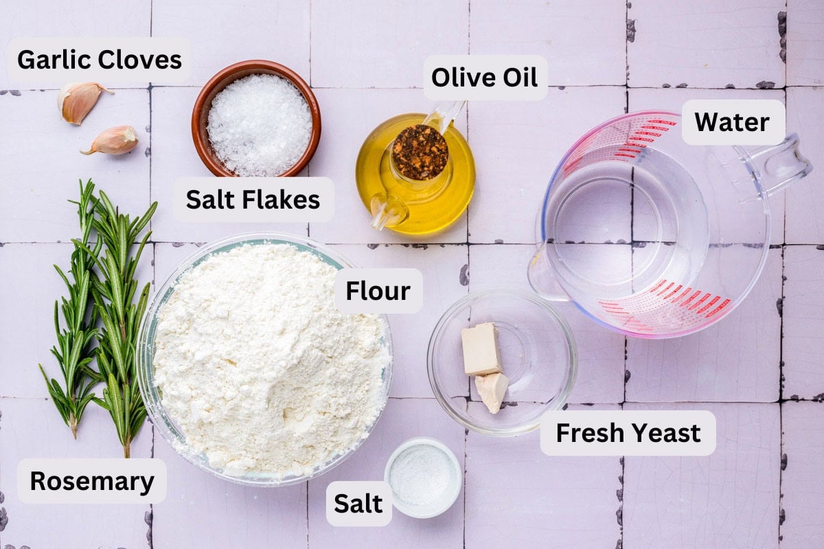 ingredients to make focaccia on counter in bowls with labels.
