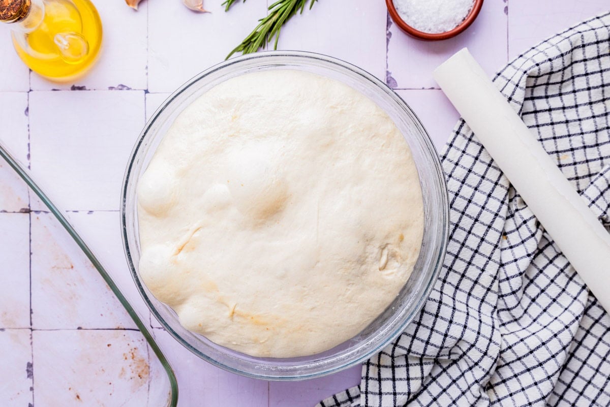expanded dough in glass bowl sitting on counter.
