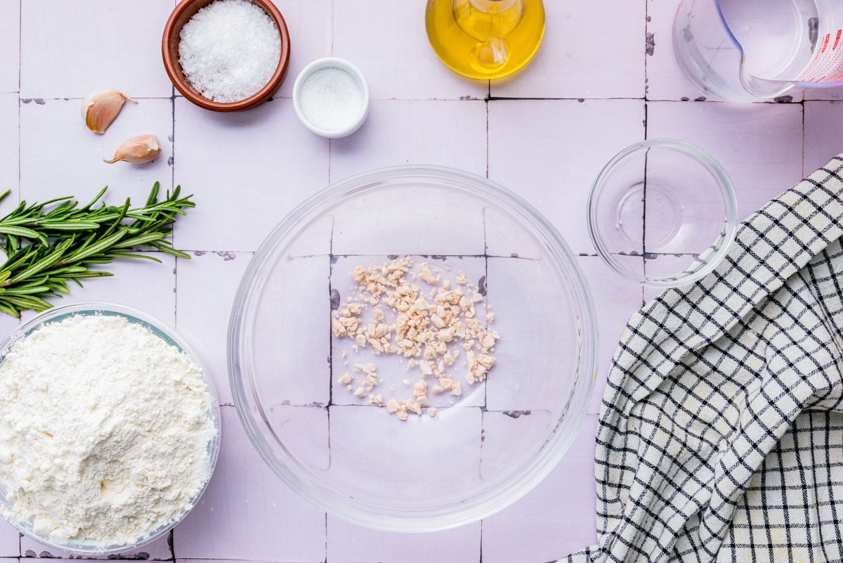 fresh yeast crumbled into clear glass bowl on counter.
