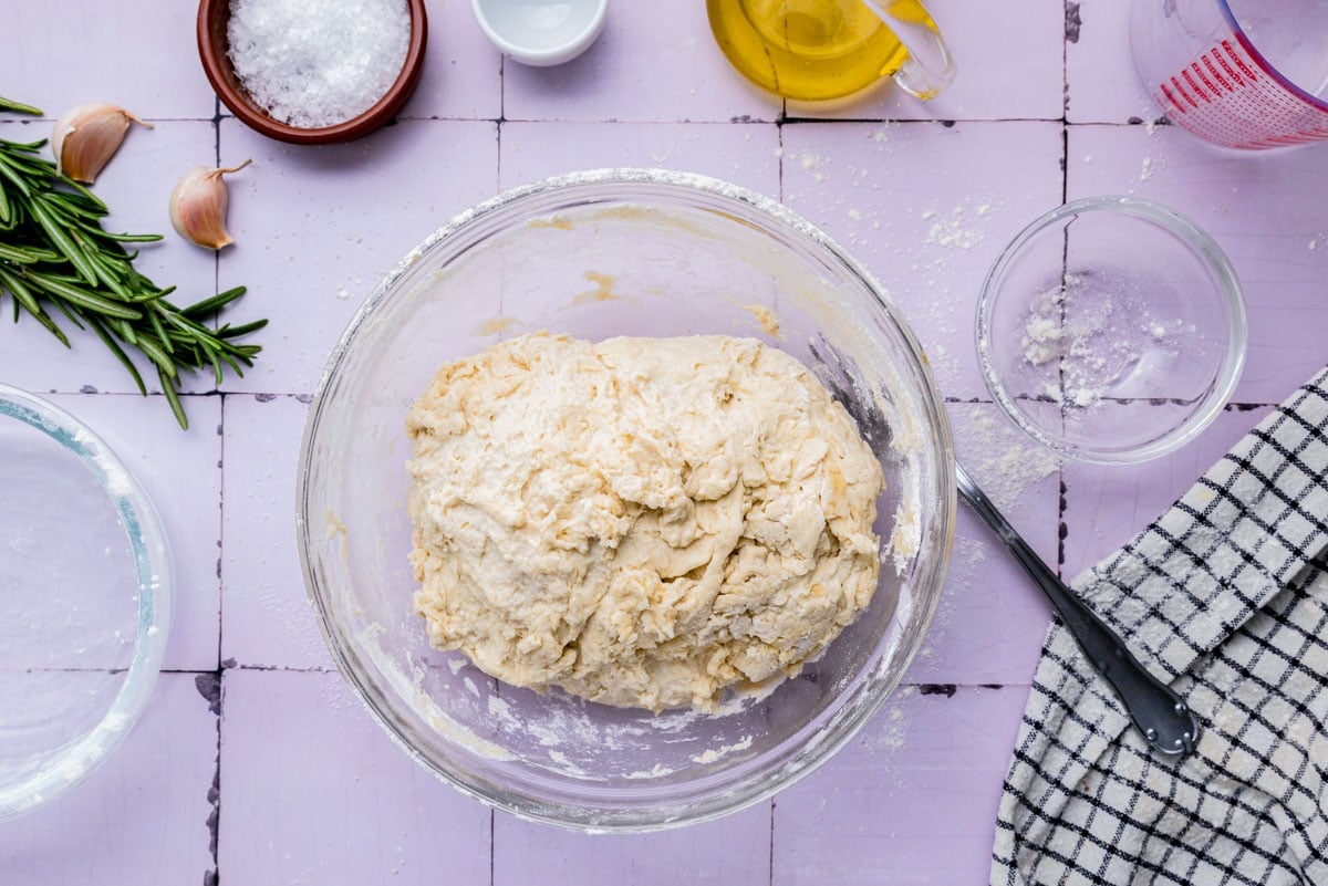 focaccia dough mixed in glass bowl on counter.