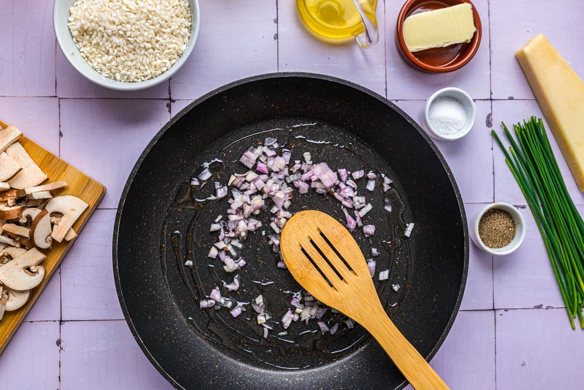 diced shallots frying in pan with wooden spoon