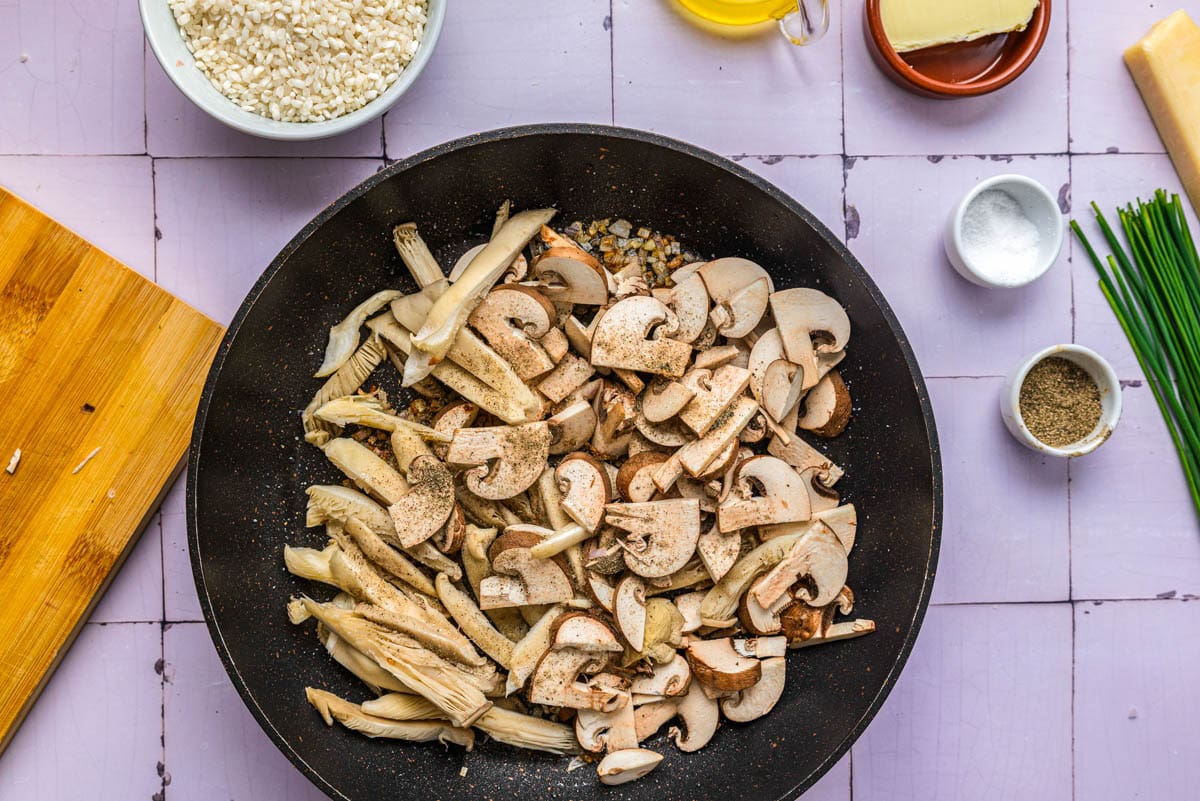 sliced raw mushrooms in frying pan with countertop around.