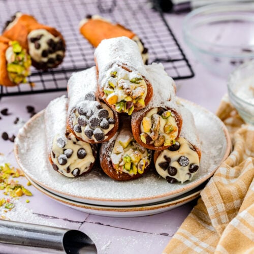 stack of cannoli covered in powdered sugar on plate.