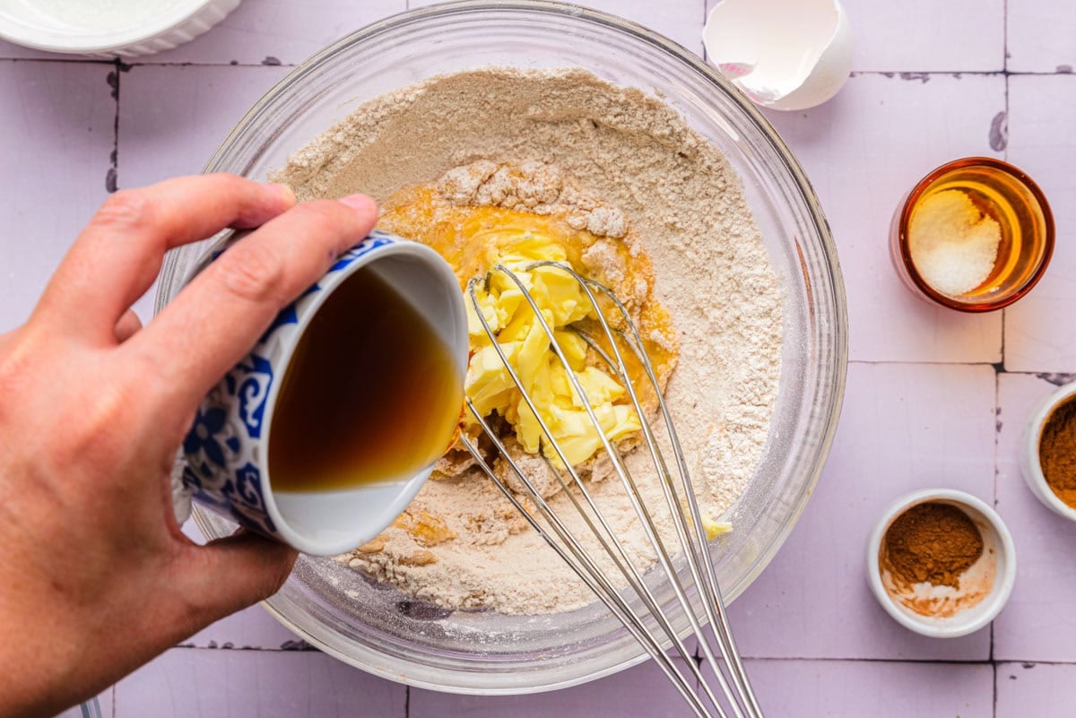 wet ingredients being added to dough in bowl on counter.