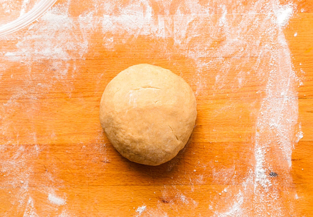 ball of dough sitting on wooden cutting board.