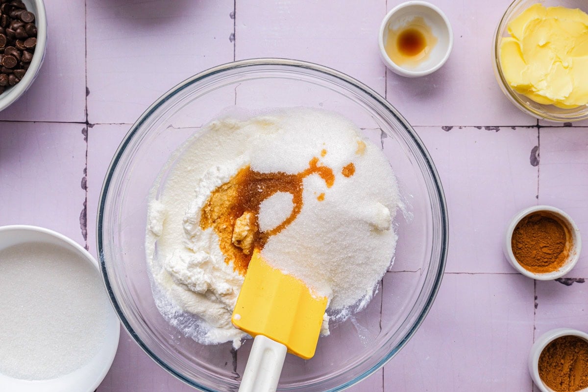 spatula moving cheese and dry ingredients in a glass bowl.