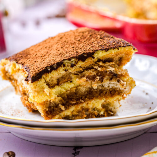 slice of layered tiramisu on plate with more in behind.