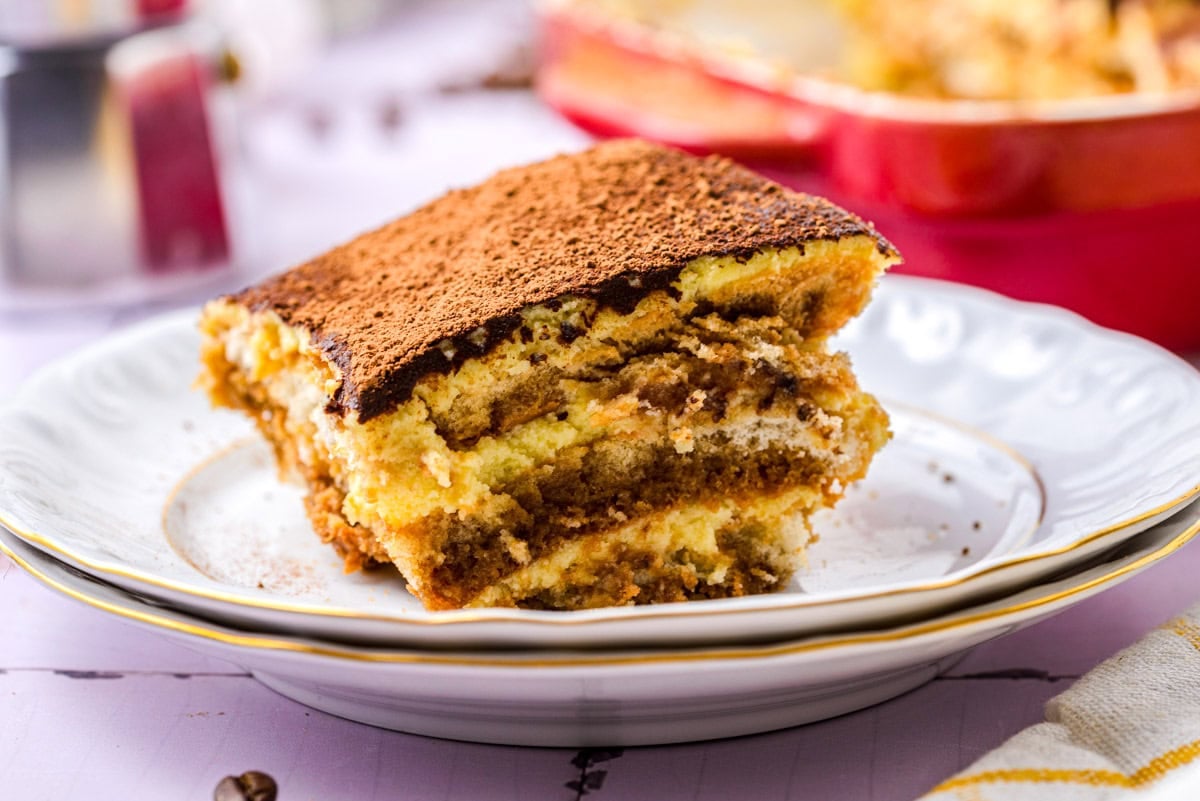 slice of layered tiramisu on plate with more in behind.