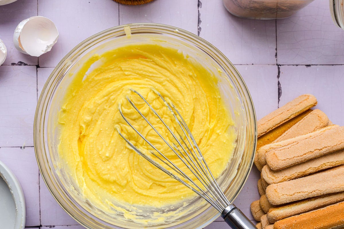 creamy cheese and yolk mixture in glass bowl on counter.