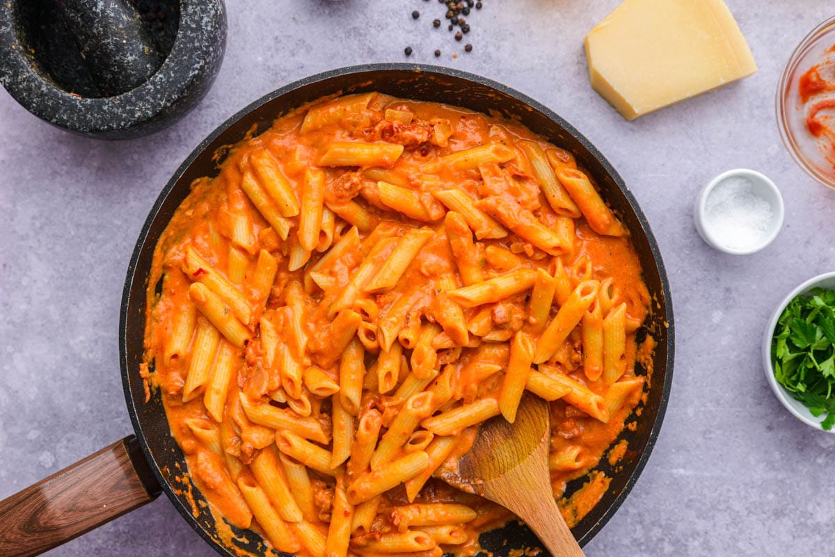 penne pasta covered in rose vodka sauce in sauce pan.