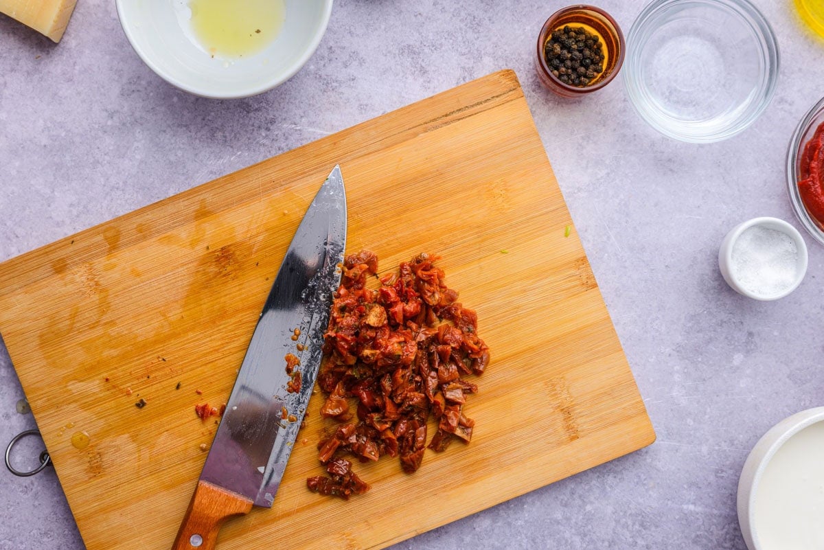 sundried tomatoes diced on wooden cutting board.
