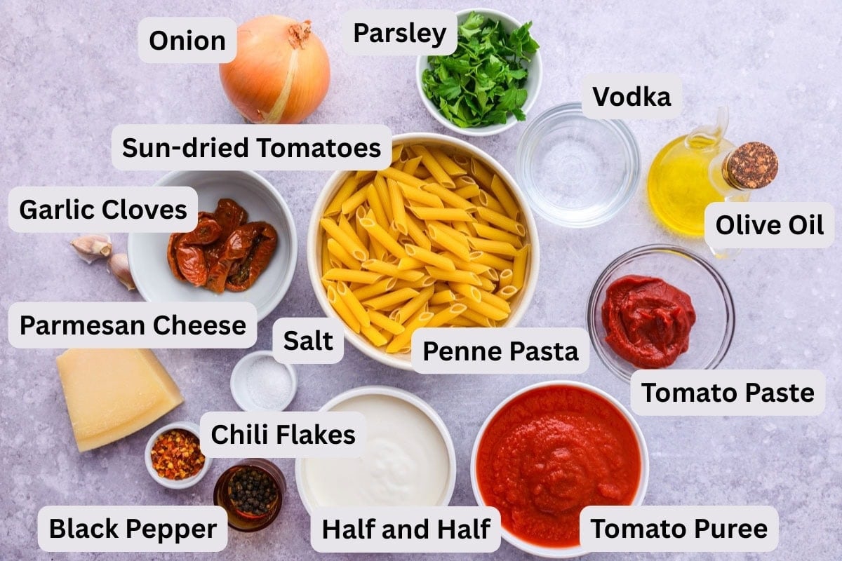 ingredients to make penne pasta with sauce in bowls on counter.