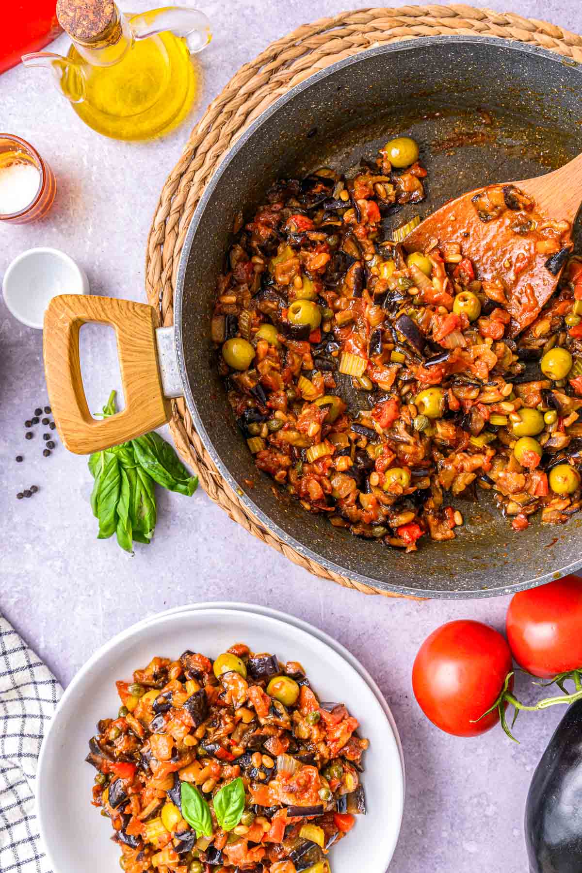 large pan of caponata stew with smaller plate of portion in front on counter.