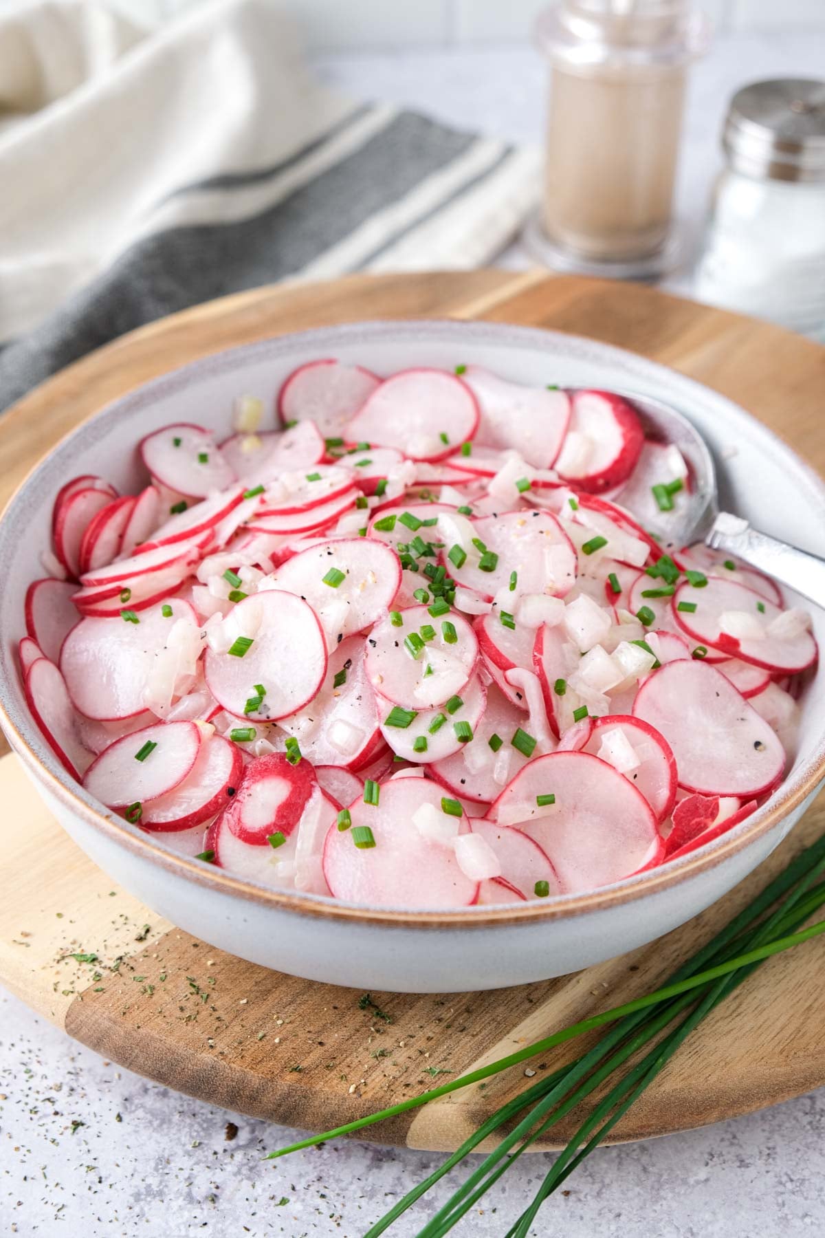 radish salad in bowl on wooden board on counter.