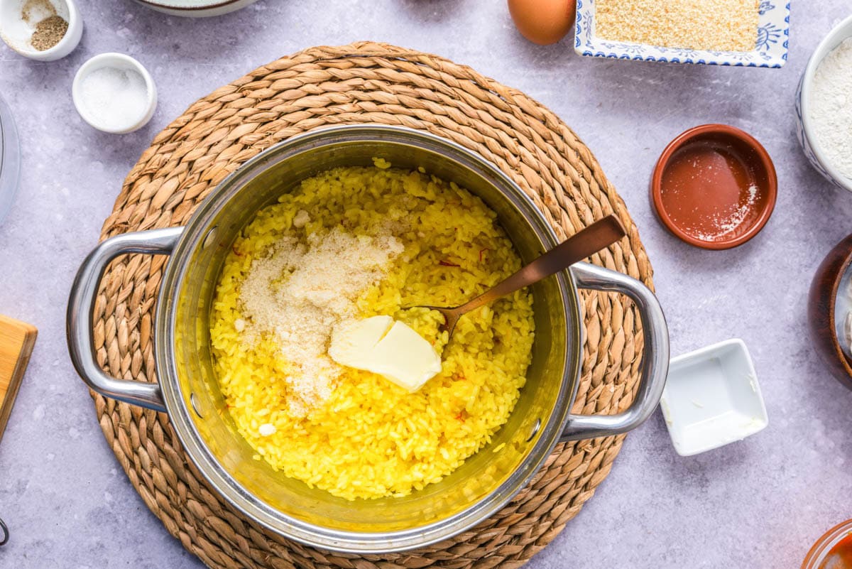 yellow rice in pot with chunk of butter added on top.