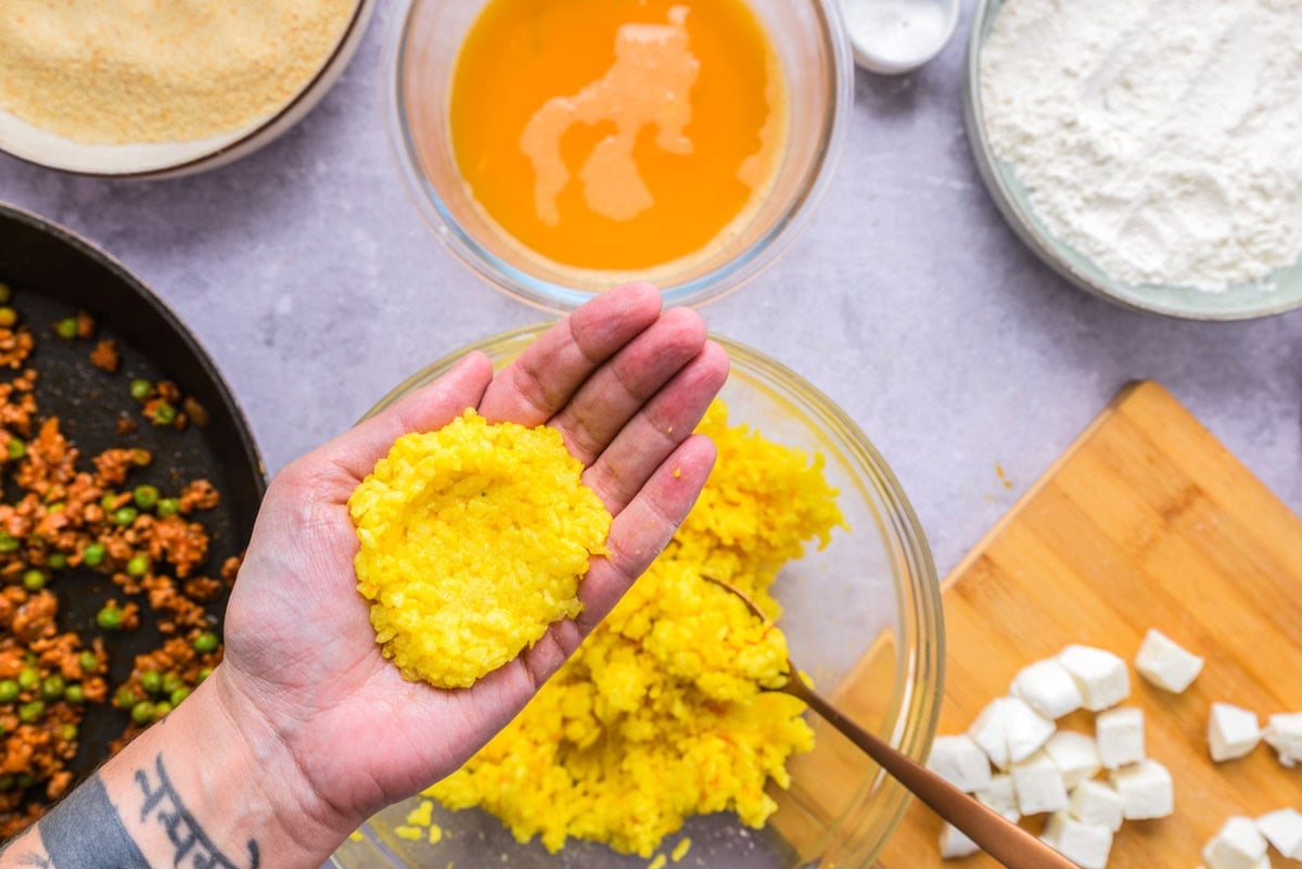 hand holding chunk of yellow rice flattened out.