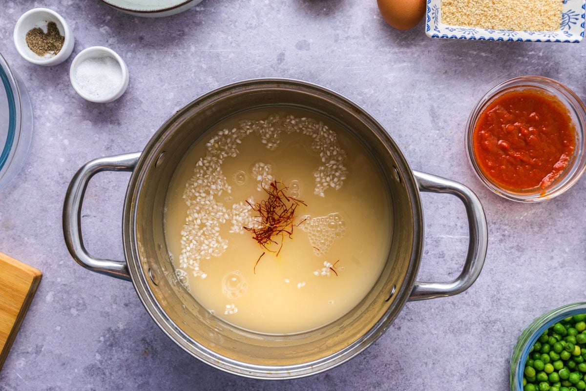 silver sauce pan filled with rice and broth and spices.