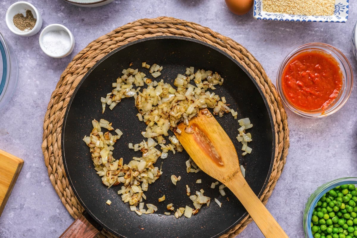 browned onions in frying pan with ingredients on counter around.