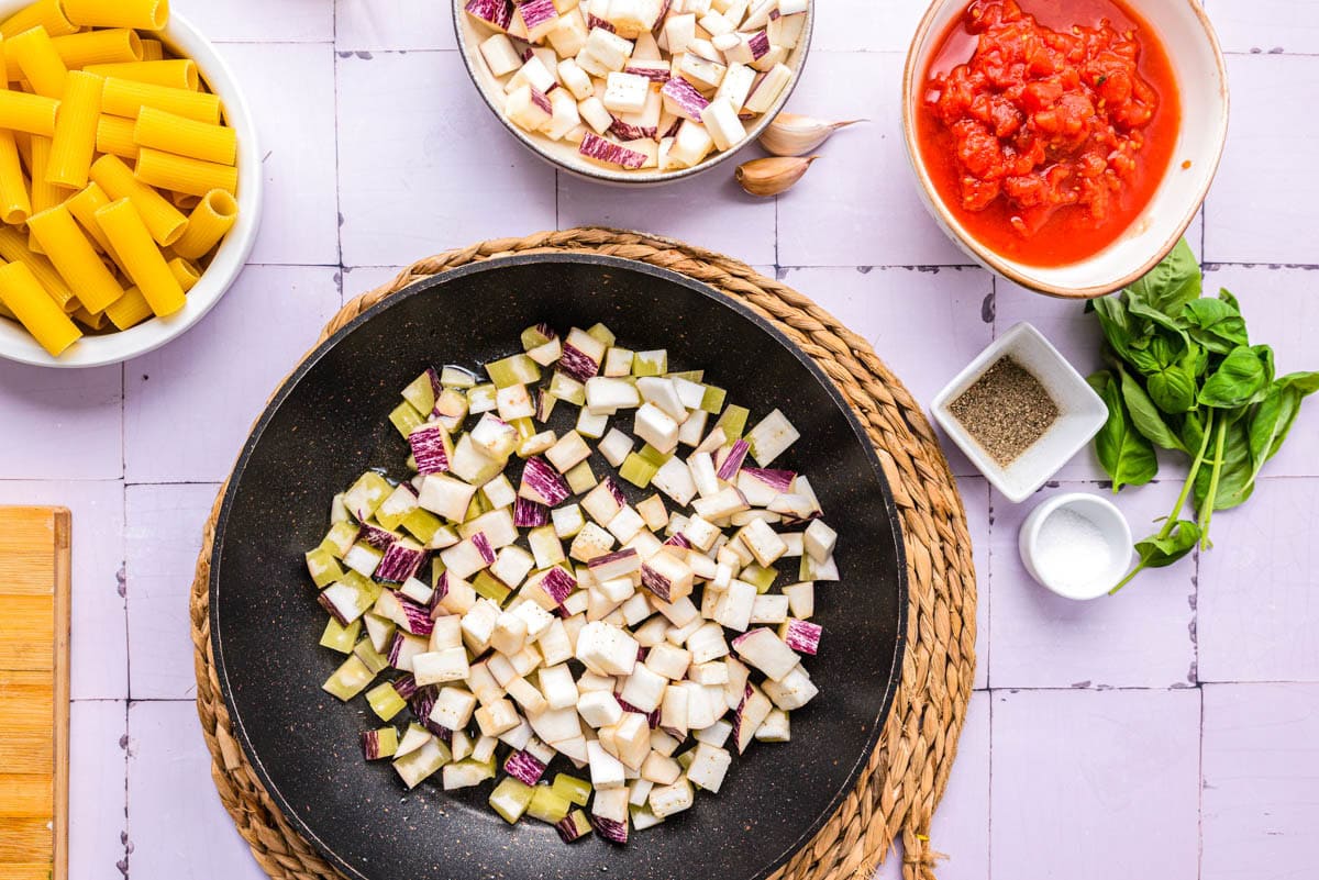 diced eggplant frying in black frying pan on counter.