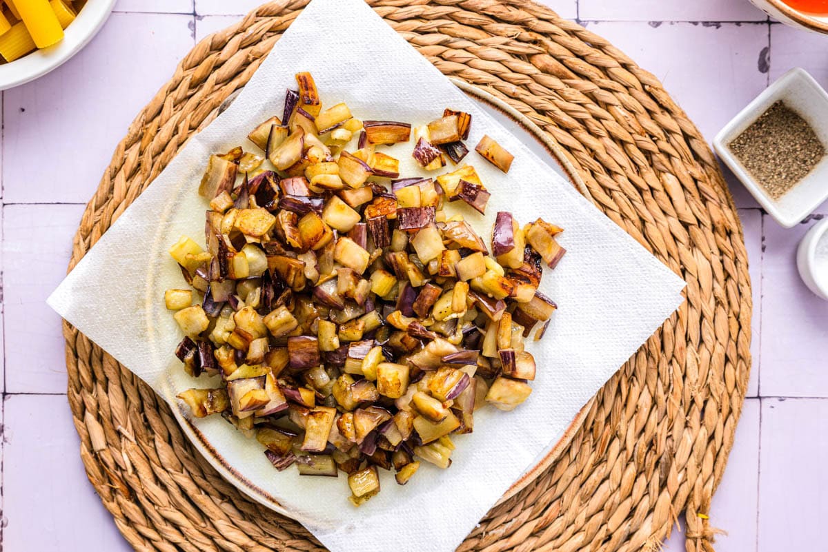 fried eggplant pieces resting on paper towel on counter.