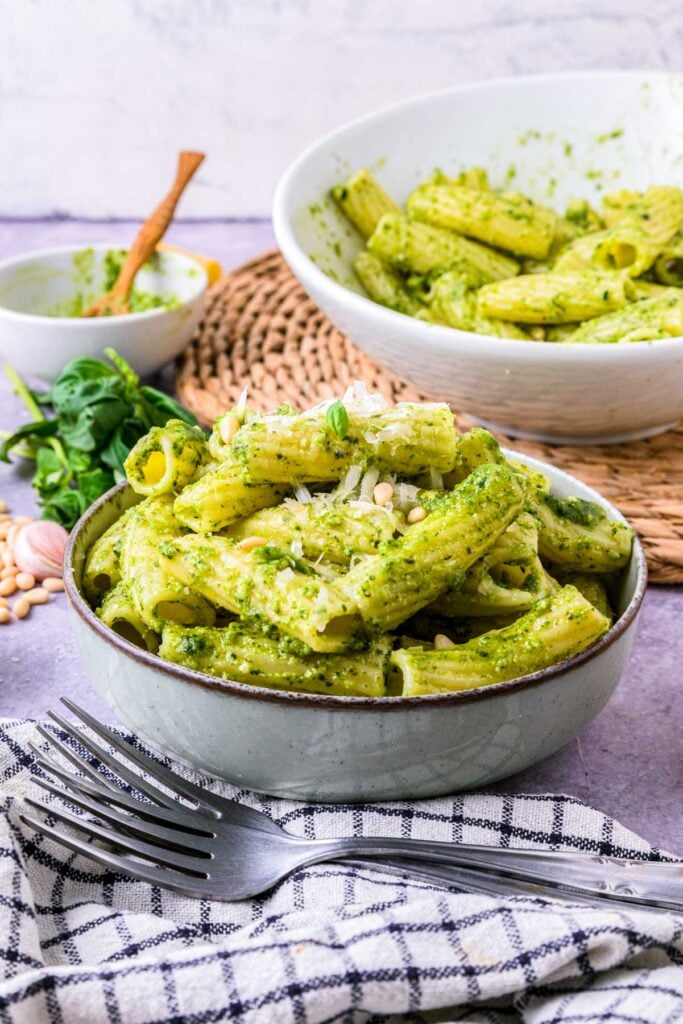 bowl of pesto pasta on counter with cloth and fork in front.