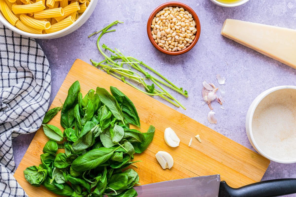garlic clove and basil cut on wooden cutting board.