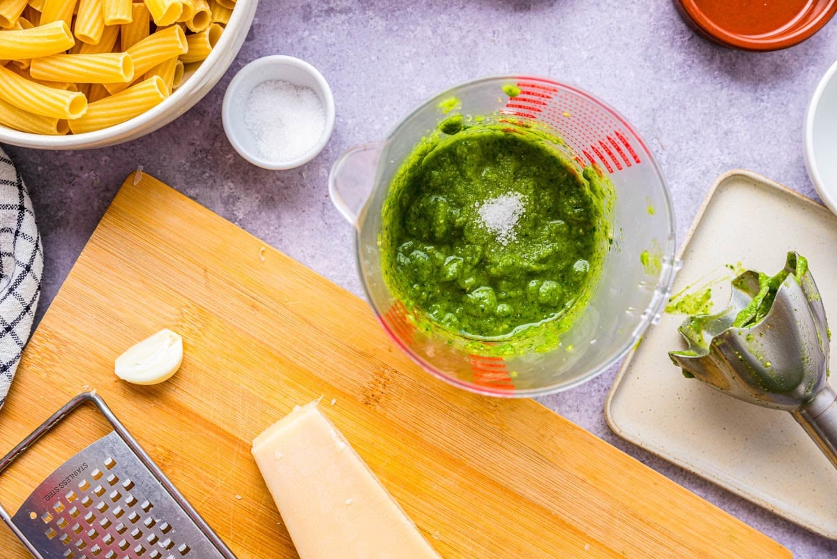 pesto sauce in mixing vessel with salt added on top.