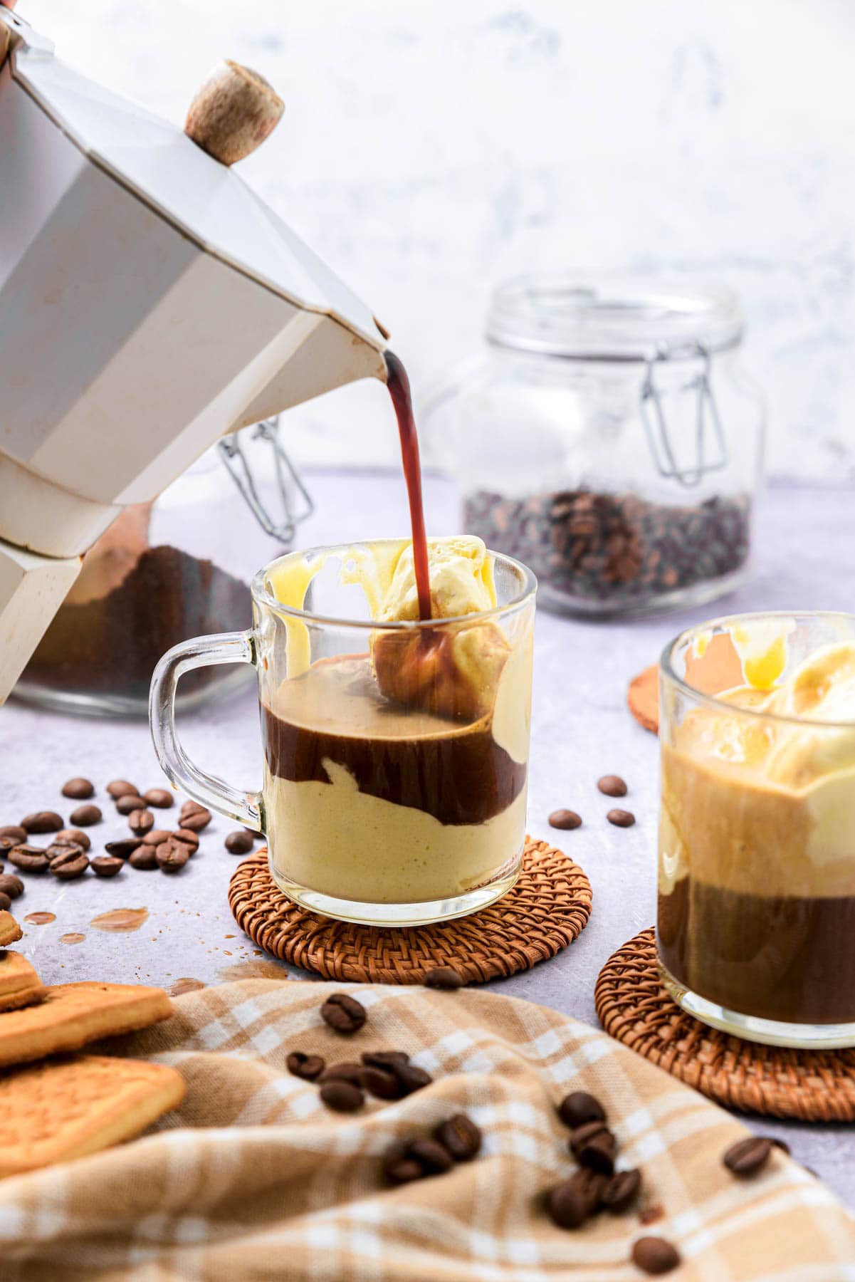 espresso being poured onto ice cream in mug on counter.
