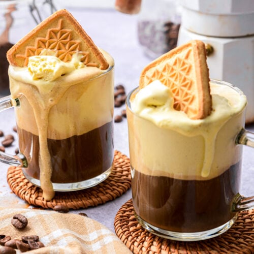 two affogato on cork coasters on counter top with coffee around.
