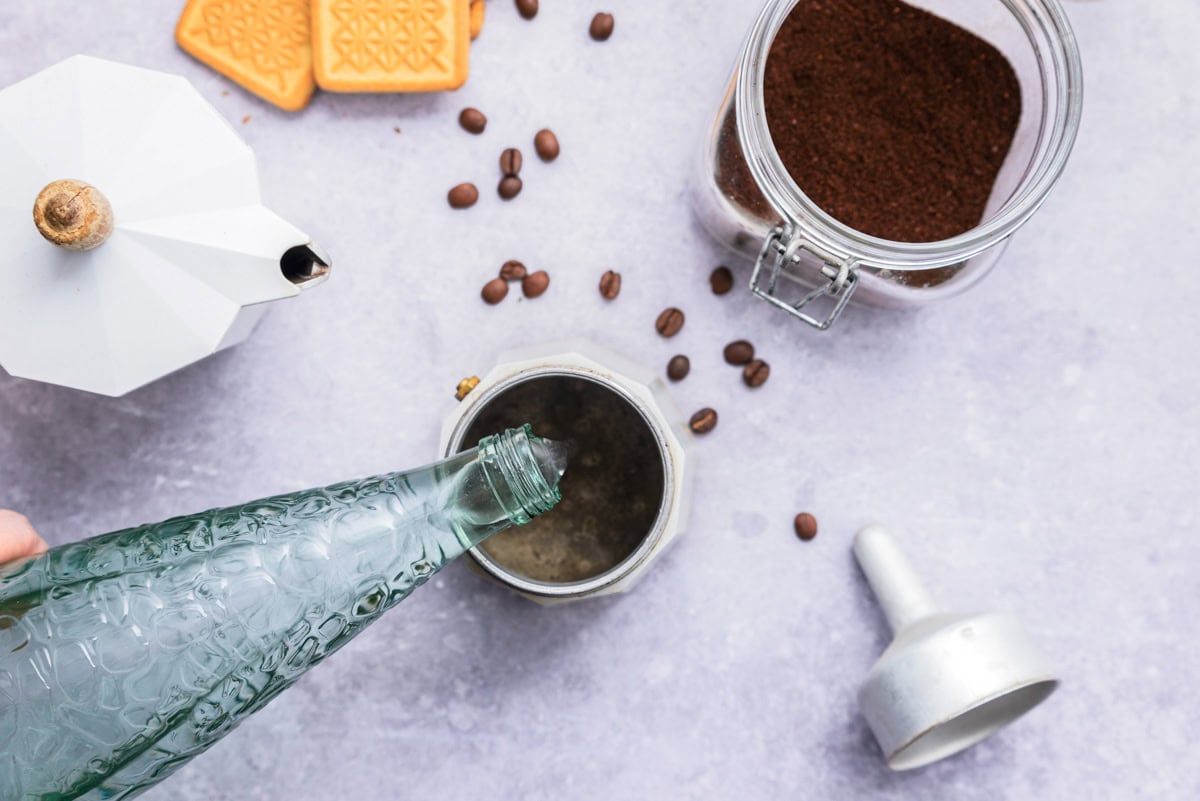 pouring water into espresso maker on counter.