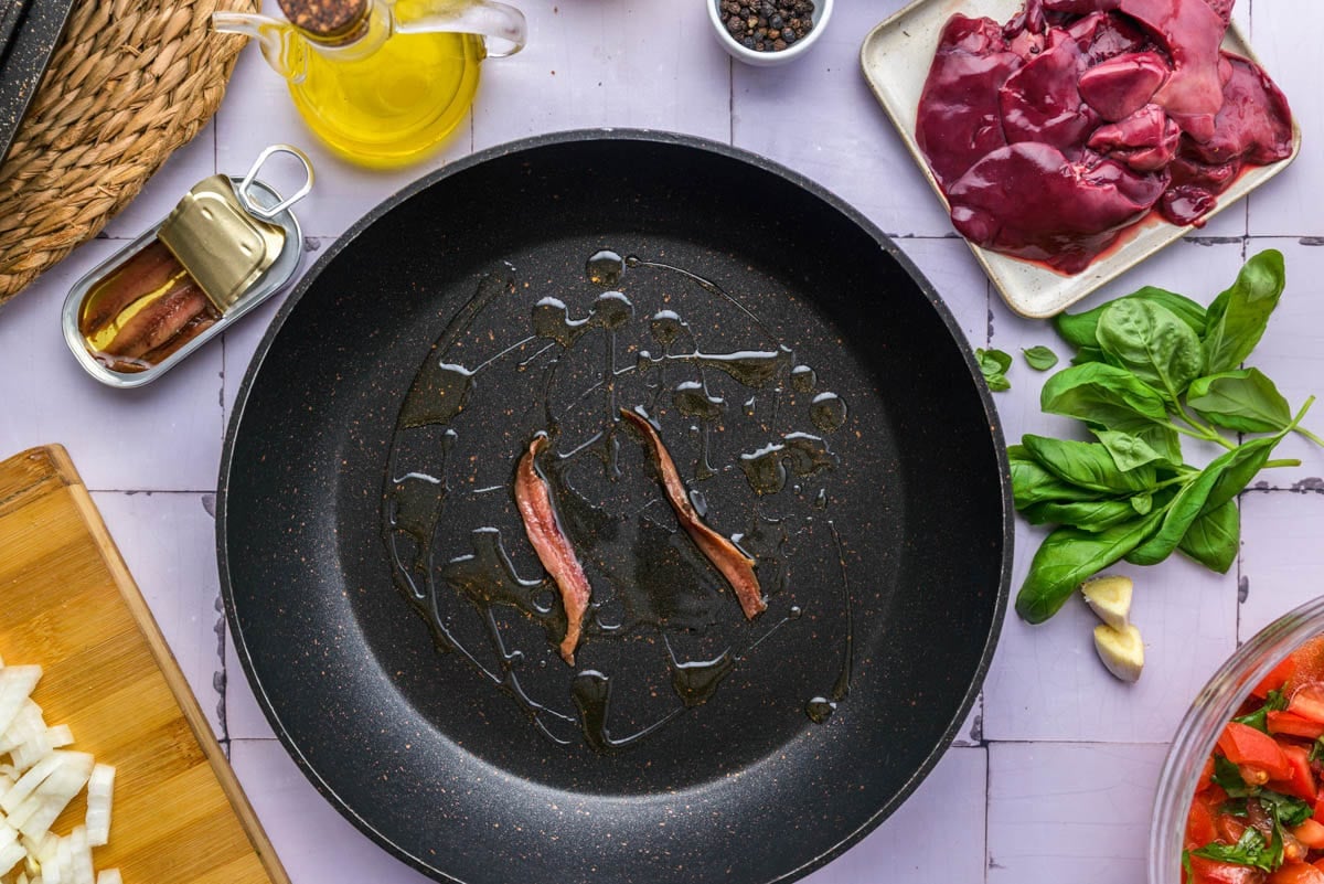 anchovies frying in black pan on counter.