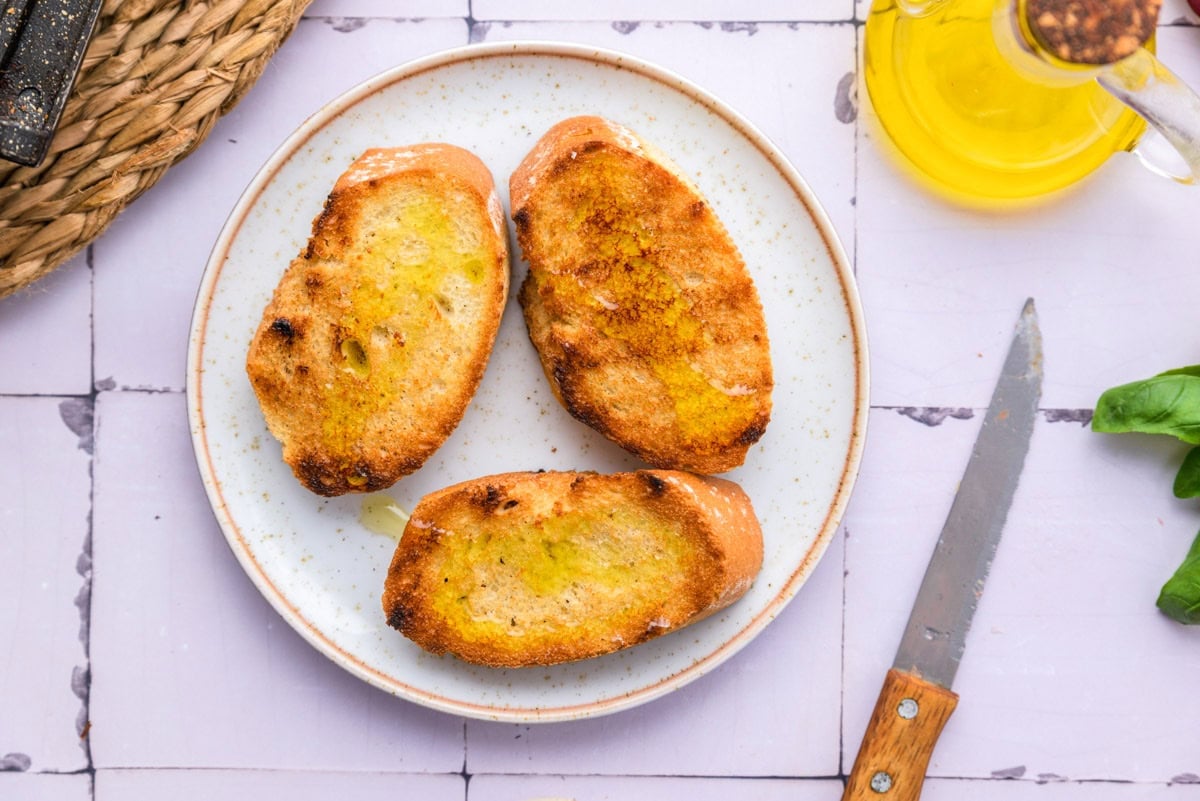 grilled bread pieces on plate drizzled in oil.