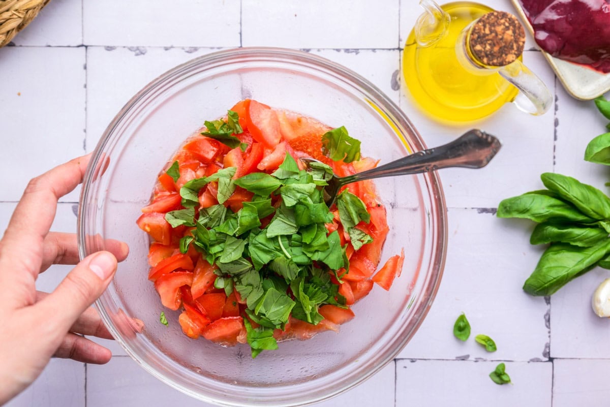 glass bowl filled with chopped fresh basil and tomatoes.